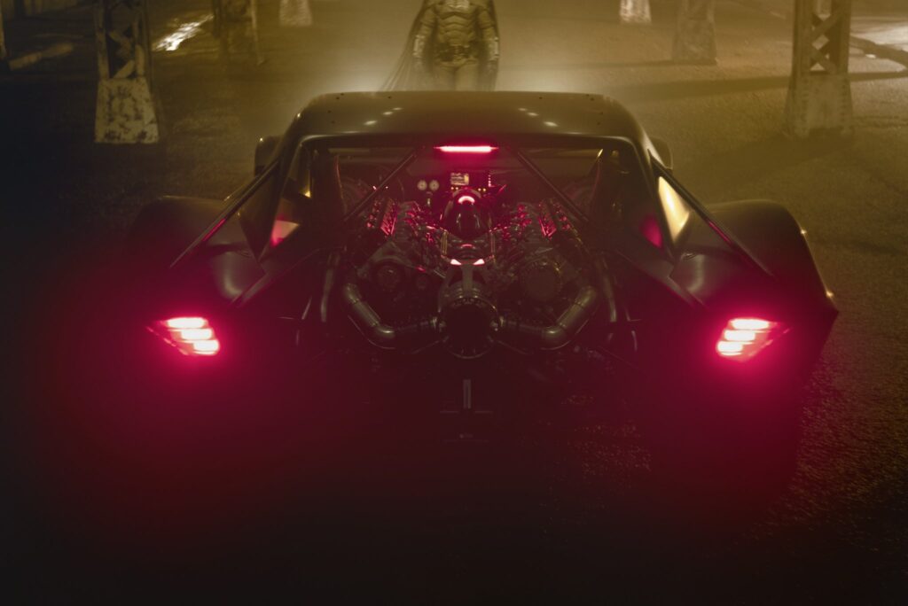 Batman in front of the Batmobile